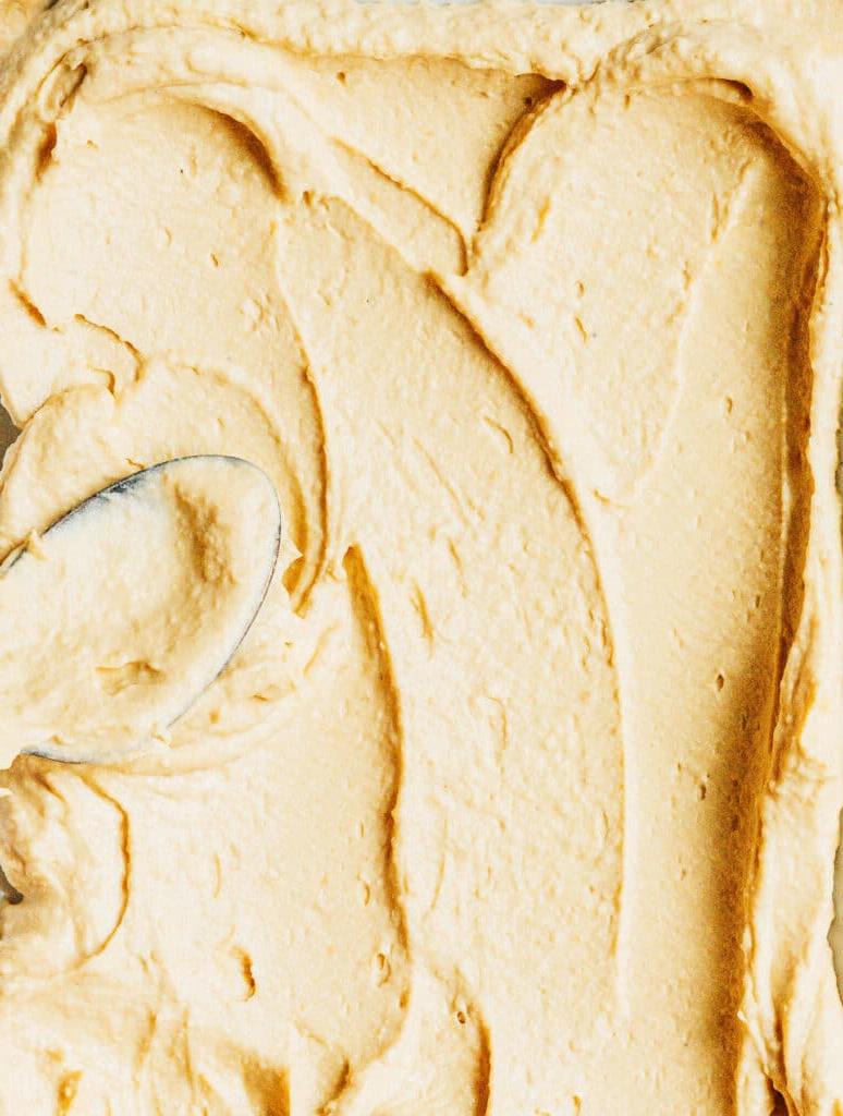 Ein Löffel verteilt Hummus auf einer Oberfläche – Nahaufnahme.