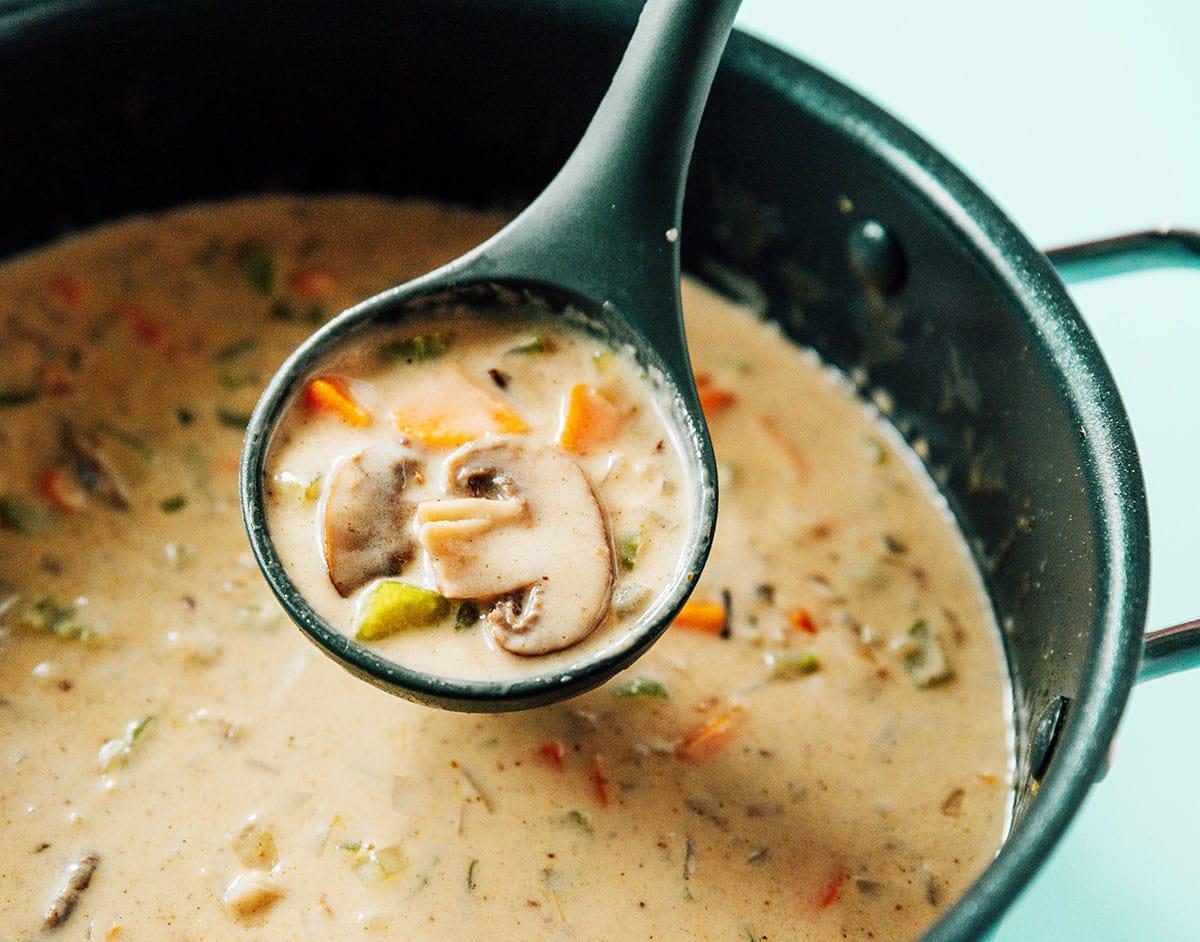 Wildreissuppe aus einem Topf schöpfen.