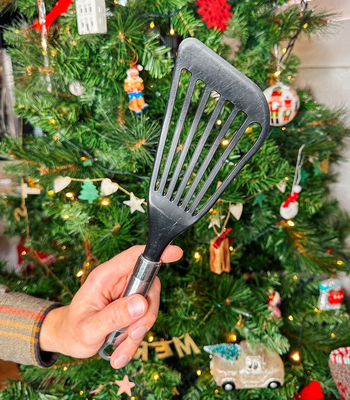 47 Geschenkideen für Feinschmecker 12 Ein flexibler Fischpfannenwender als Geschenk vor einem Weihnachtsbaum.