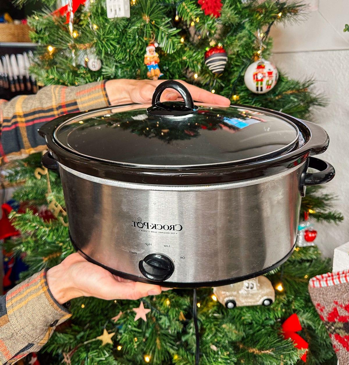 47 Geschenkideen für Feinschmecker 13 Ein Crock-Pot Slow Cooker als Geschenk vor einem Weihnachtsbaum.