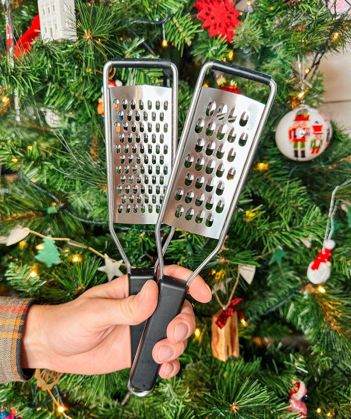 47 Geschenkideen für Feinschmecker 15 Verschiedene Käsereiben als Geschenk vor einem Weihnachtsbaum.