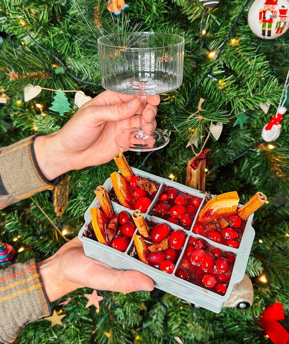 47 Geschenkideen für Feinschmecker 18 Riesige Eiswürfel in Cocktailgläsern (Cranberry Aperol Spritz) als Geschenk vor einem Weihnachtsbaum.