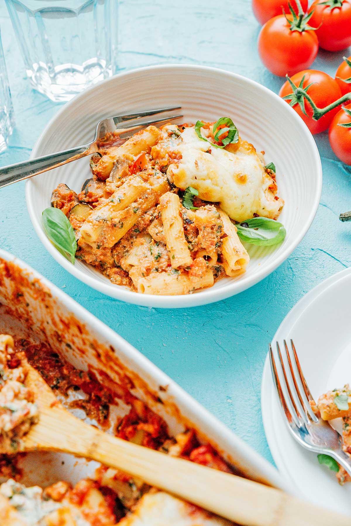 Eine käsige Portion gebackenes Ziti, garniert mit Basilikum