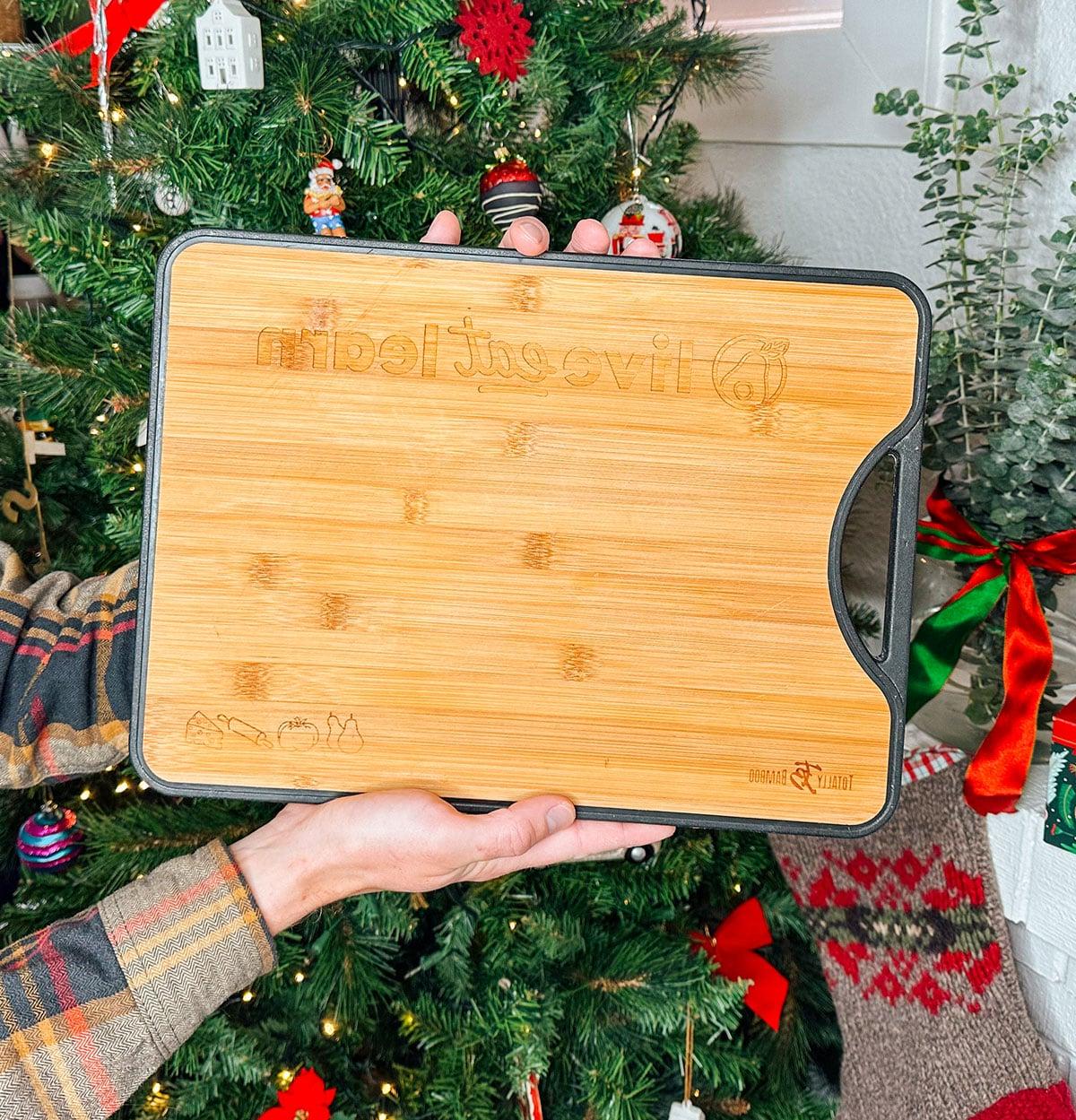 47 Geschenkideen für Feinschmecker 3 Ein persönlich graviertes Schneidebrett als Geschenk vor einem Weihnachtsbaum.