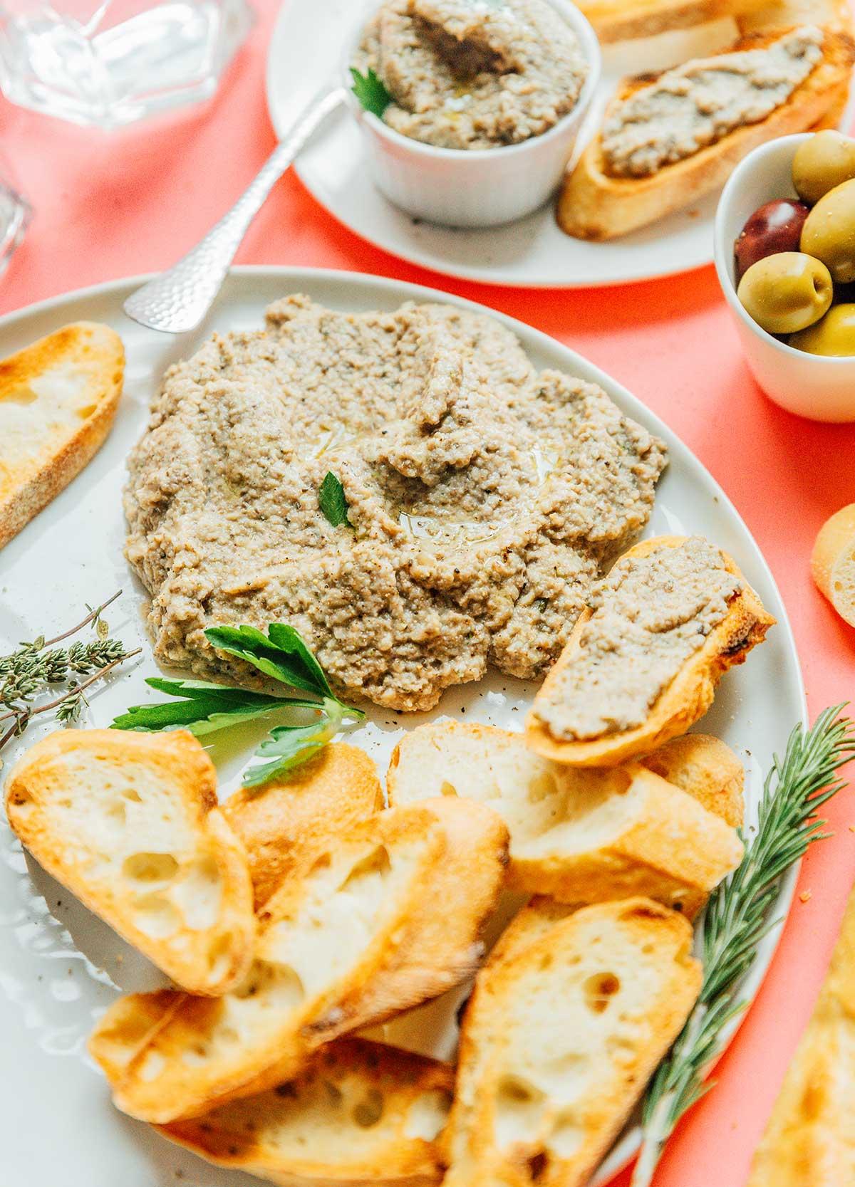 Ein großer Klecks Pilzpastete auf einem weißen Teller mit Scheiben von französischem Brot