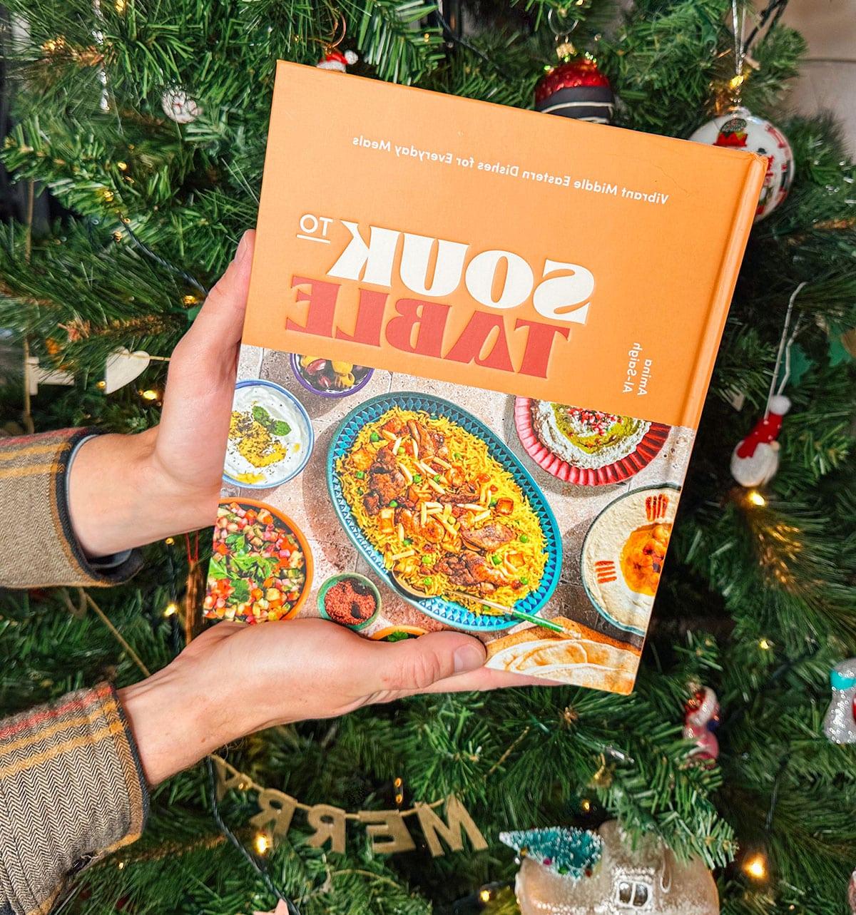 47 Geschenkideen für Feinschmecker 23 Das Kochbuch 'Souk to Table' als Geschenk vor einem Weihnachtsbaum.