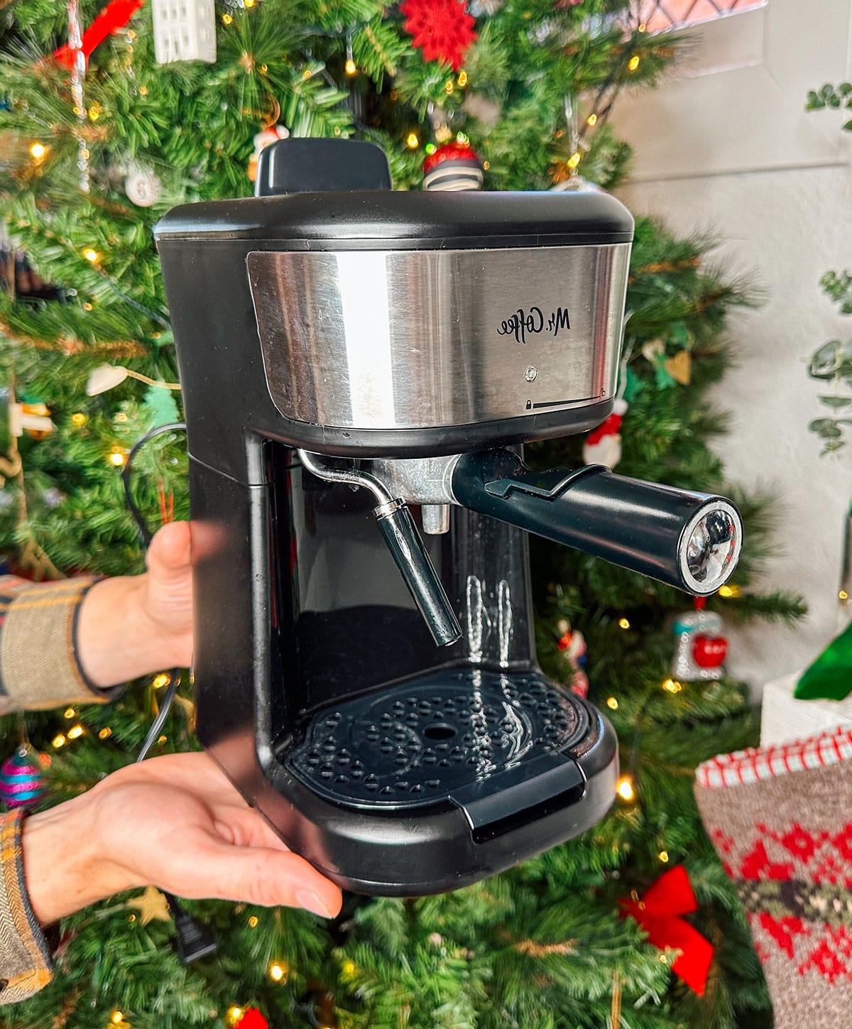 47 Geschenkideen für Feinschmecker 27 Eine Mr. Coffee Espressomaschine als Geschenk vor einem Weihnachtsbaum.