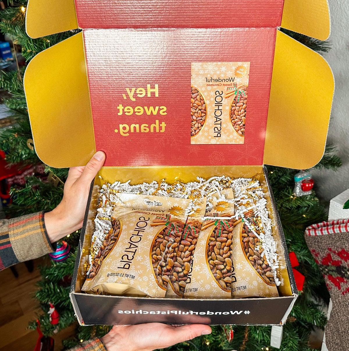 47 Geschenkideen für Feinschmecker 28 Wonderful Pistazien mit Zimtgeschmack als Geschenk vor einem Weihnachtsbaum.
