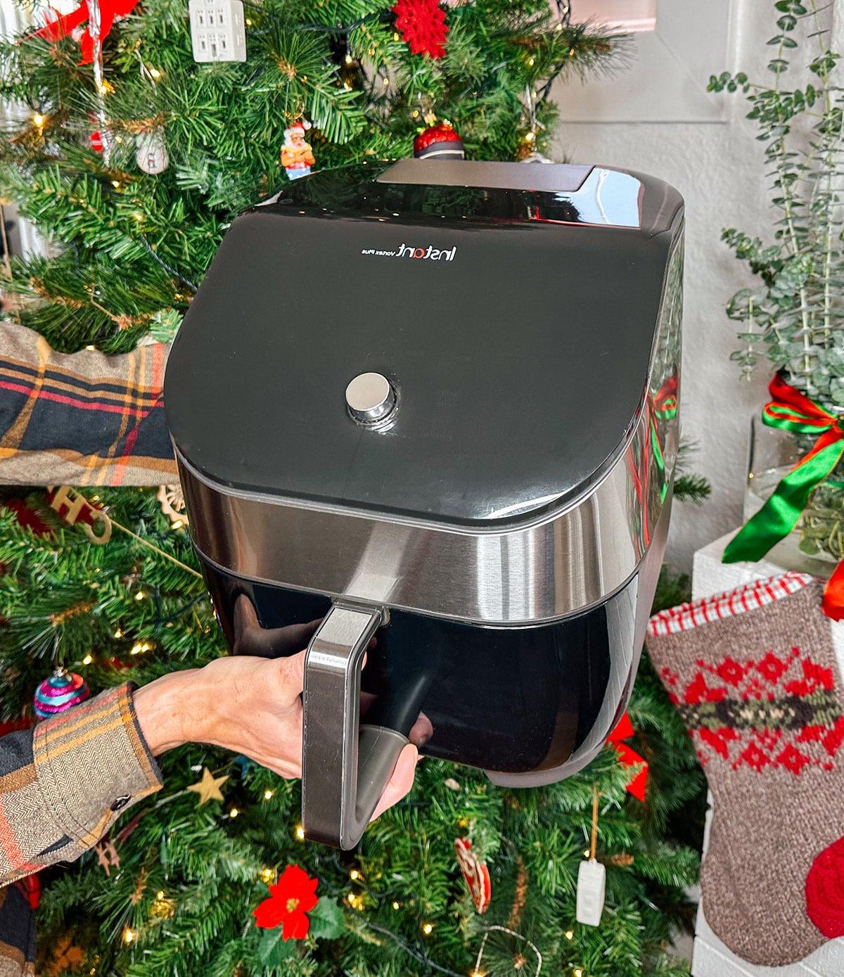 47 Geschenkideen für Feinschmecker 4 Eine Instant Vortex Heißluftfritteuse als Geschenk vor einem Weihnachtsbaum.