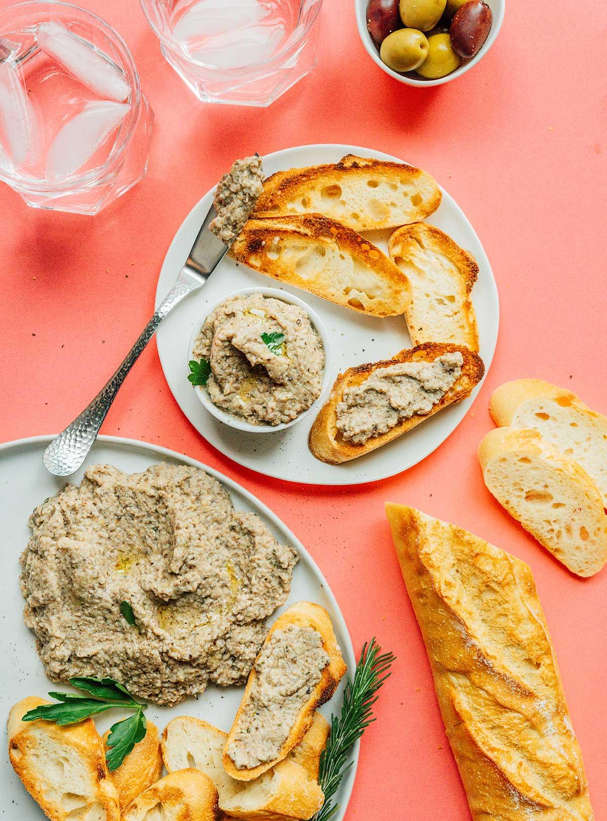 Eine kleine Schale Pilzpastete auf einem weißen Teller mit Scheiben von französischem Brot