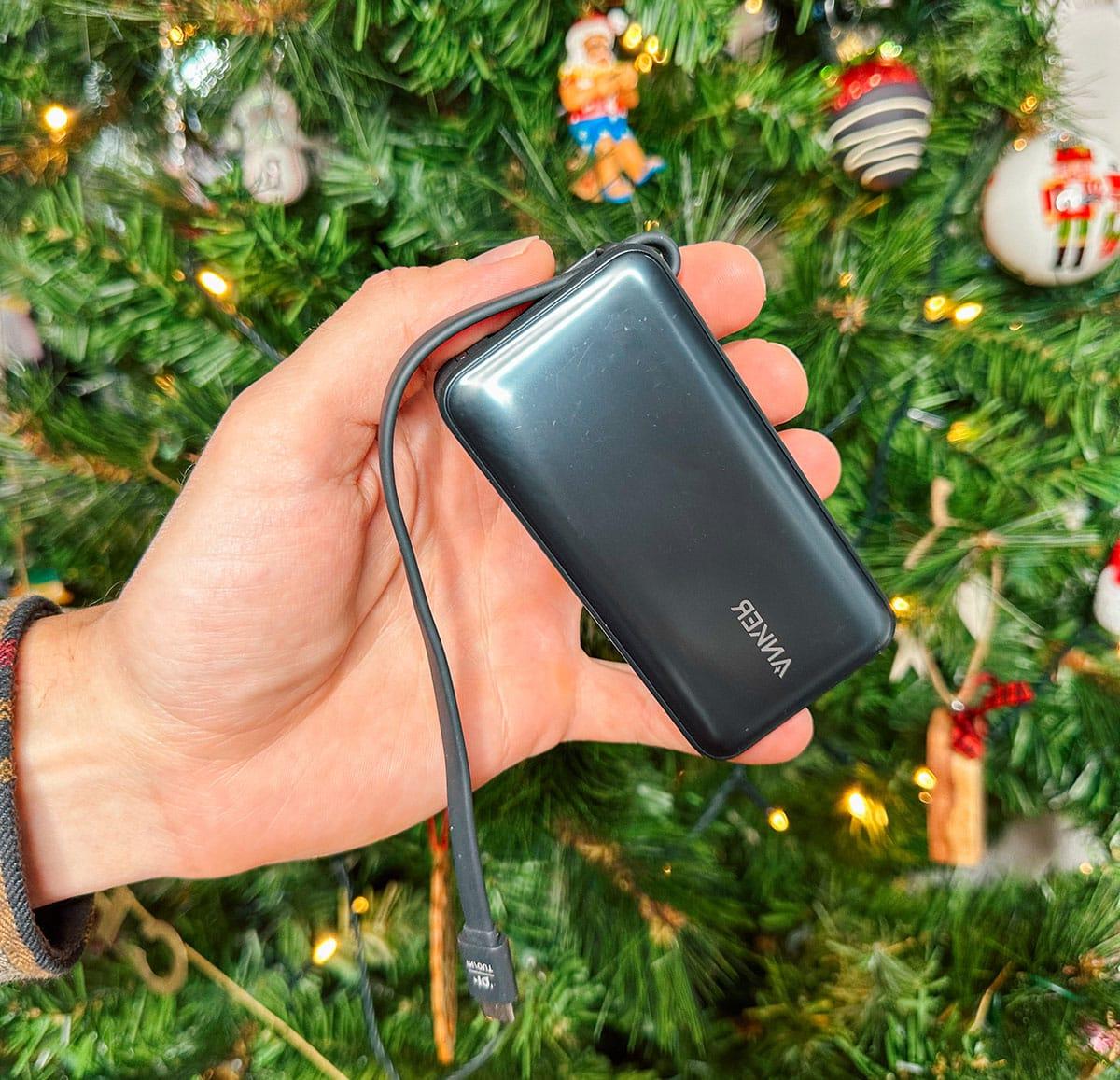 47 Geschenkideen für Feinschmecker 38 Ein tragbares Ladegerät von Anker als Geschenk vor einem Weihnachtsbaum.