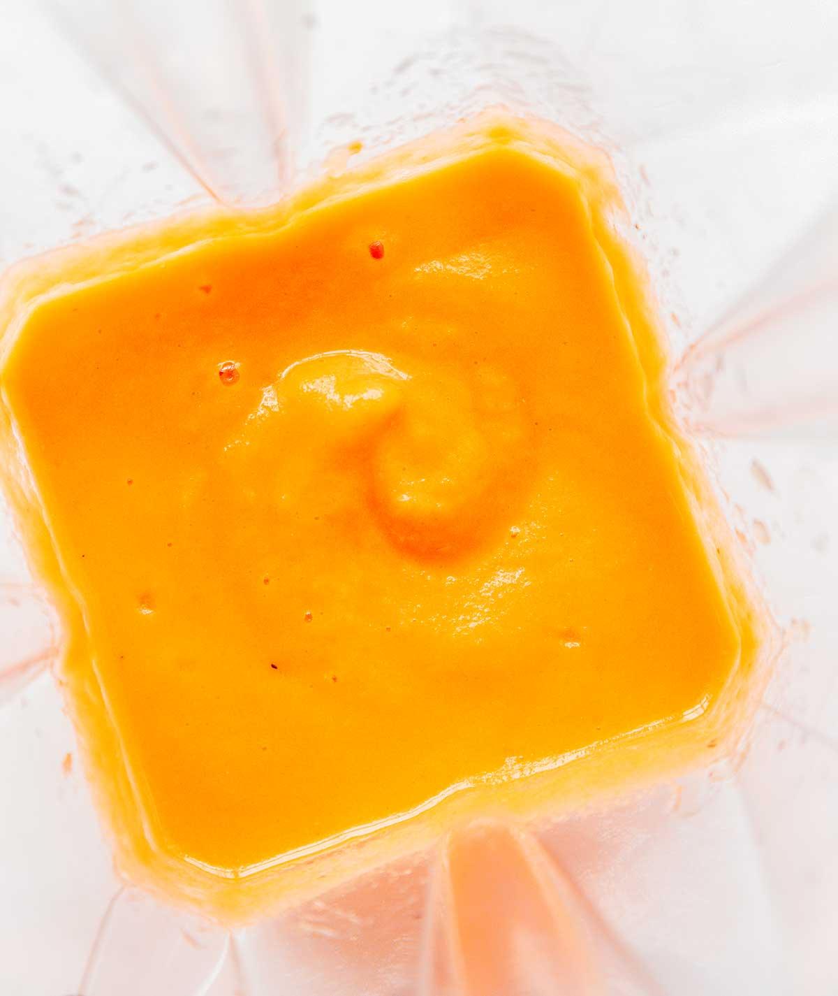 Karotten-Ingwer-Smoothie 5 Ein Mixer gefüllt mit frisch gemischtem Karotten-Smoothie mit Zitrusfrüchten und Ingwer