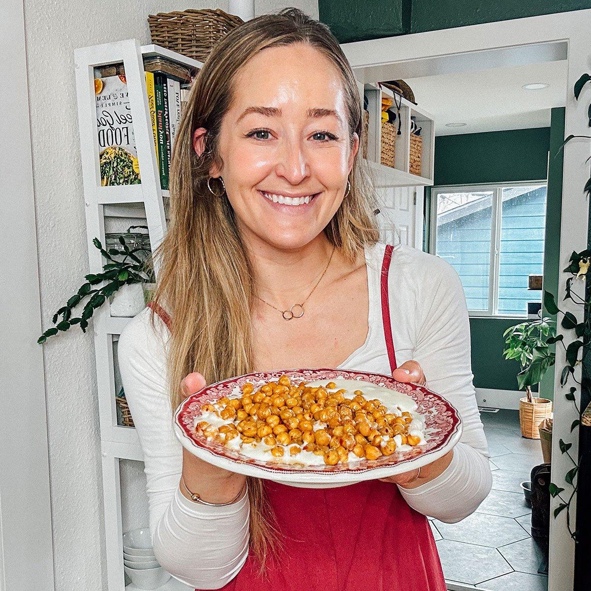 Sarah hält einen Teller mit Hot Honey gerösteten Kichererbsen.