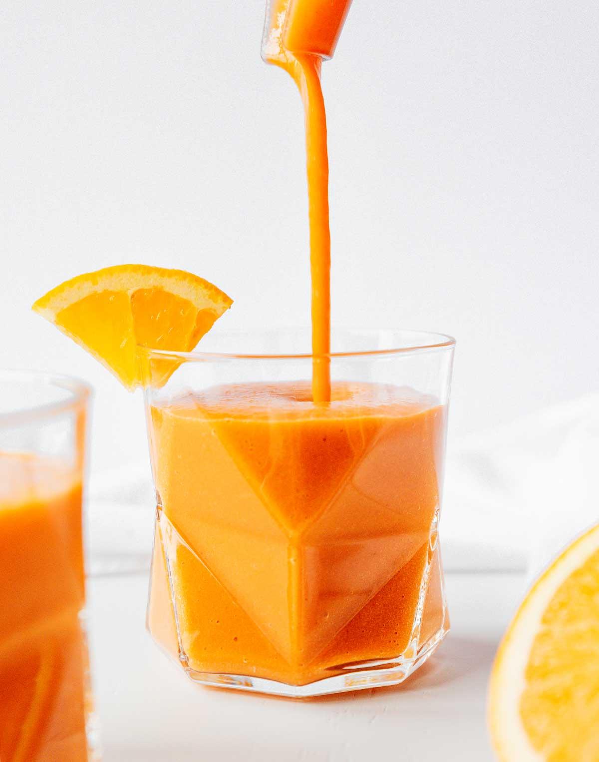 Karotten-Ingwer-Smoothie 6 Karotten-Smoothie mit Zitrusfrüchten und Ingwer aus einem Mixer in ein Glas gießen