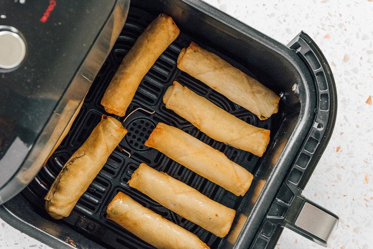 Frühlingsrollen in einem Heißluftfritteusenkorb mit Abstand zueinander angeordnet.