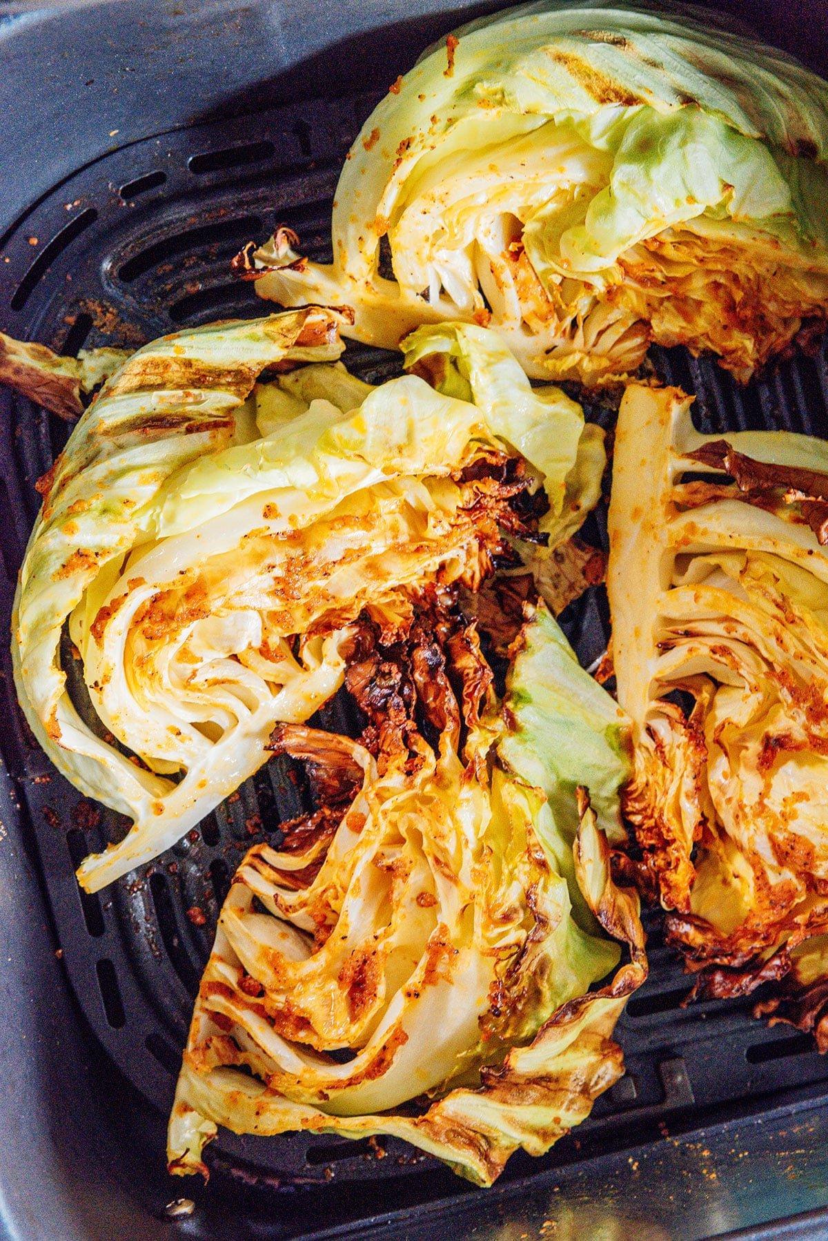 Fertige Kohlspalten aus der Heißluftfritteuse in einem Airfryer-Korb.