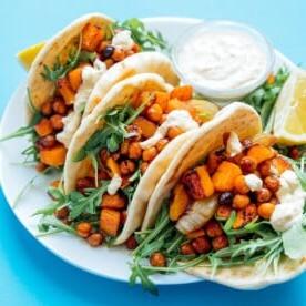 Butternut-Wraps auf einem Teller mit blauem Hintergrund – würziger, herzhafter Geschmack, eingewickelt in warme Fladenbrote – das ist das Motto dieser gerösteten Butternut-Kichererbsen-Hummus-Wraps!