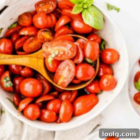 photo showing a spoon over a bowl full of italian tomato salad with juicy fresh tomatoes and fresh basil ready to serve it up