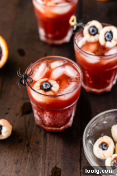 Glass of Halloween punch with lychee eyeballs and a spooky straw