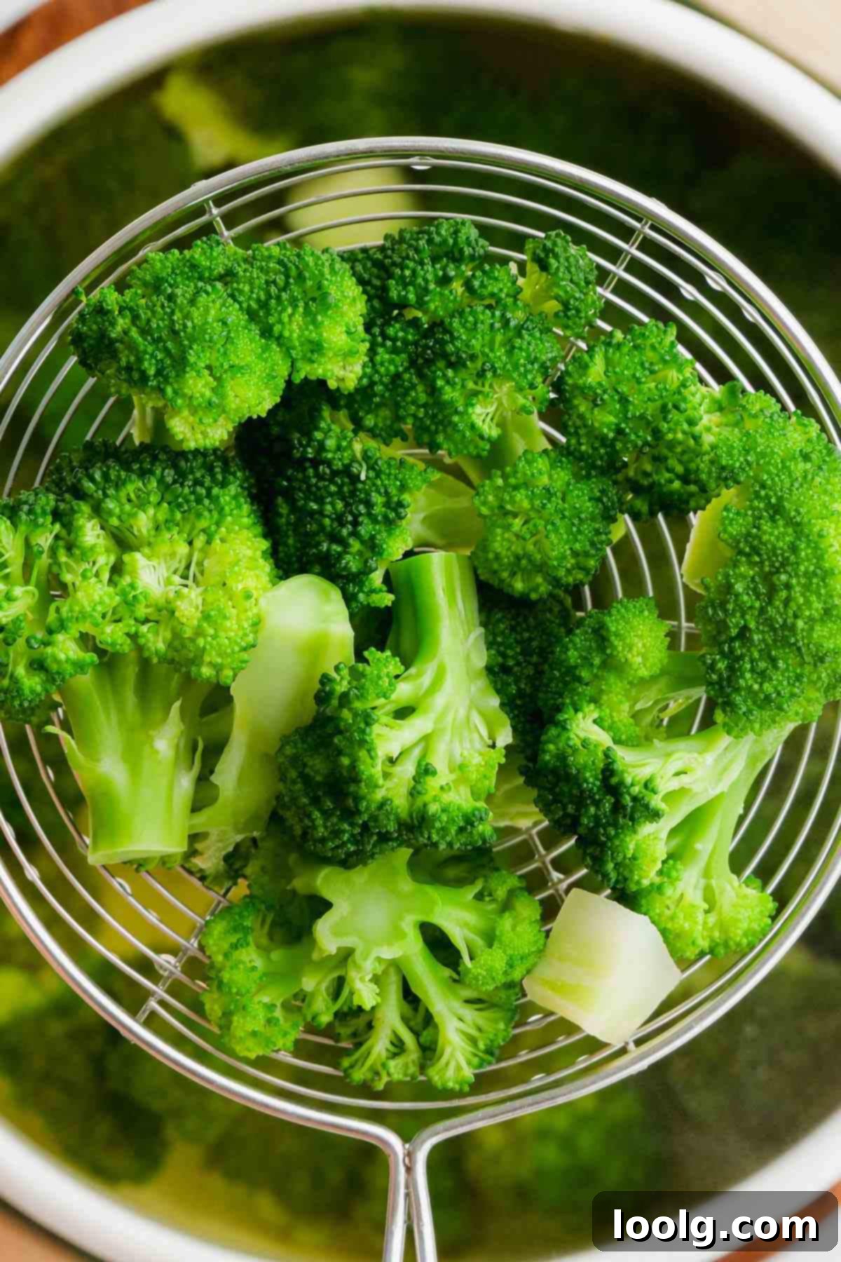 A slotted spoon carefully removing vivid green blanched broccoli florets from boiling water.