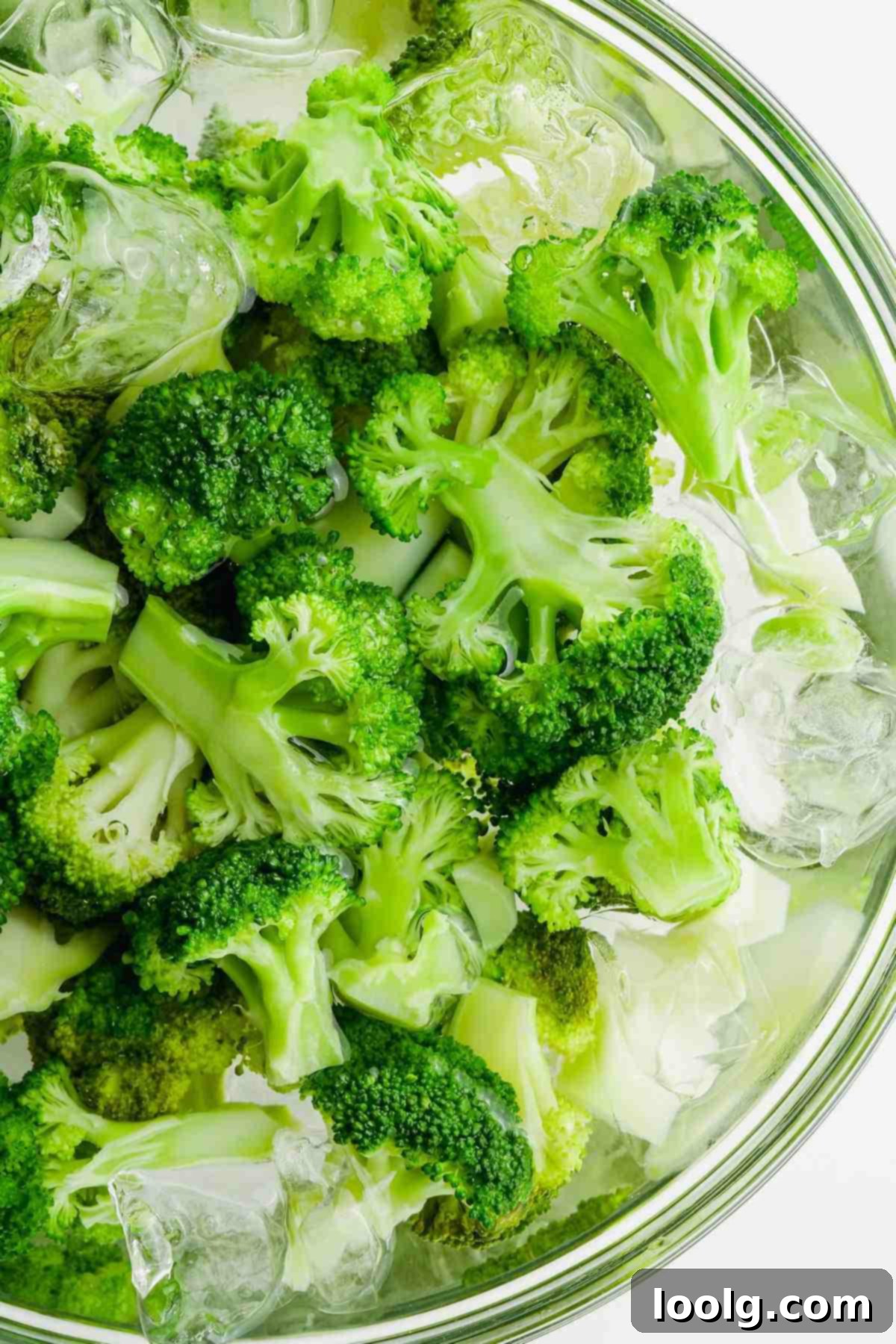 Blanched broccoli florets submerged in a bowl of ice water, the 'shocking' process.