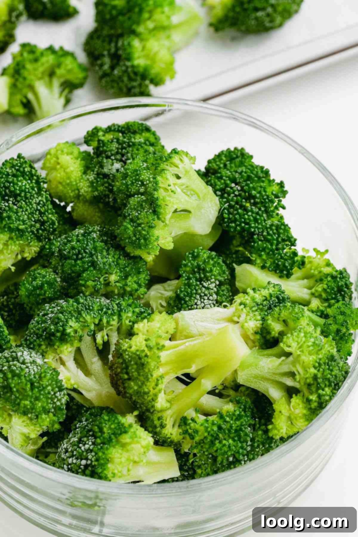 A glass bowl filled with vibrant green, perfectly blanched broccoli florets, ready for consumption or freezing.