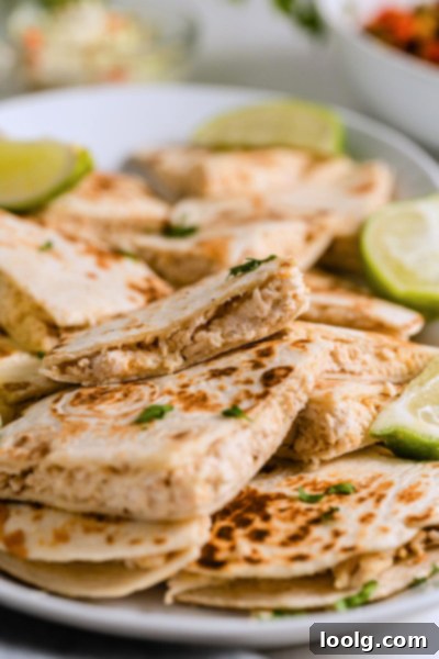 A close-up shot of the gooey, melted cheese and chicken filling inside a warm cream cheese quesadilla, revealing its creamy texture.