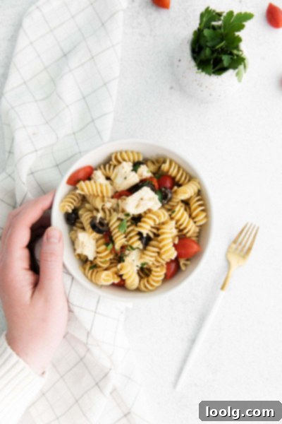 hand hold bowl of greek style pasta salad