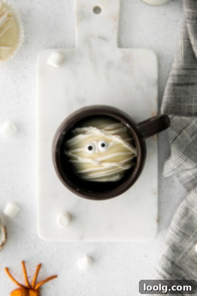Several Halloween Hot Chocolate Bombs in a white ceramic bowl, showcasing the mummy decoration from different angles.