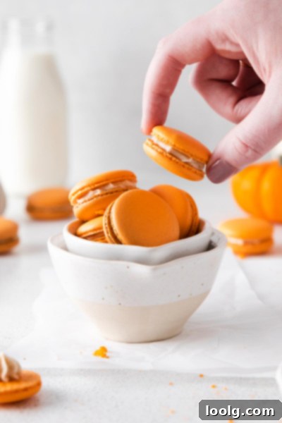 Pumpkin Spice Macarons with Jack-o-lantern faces, stacked on a plate.