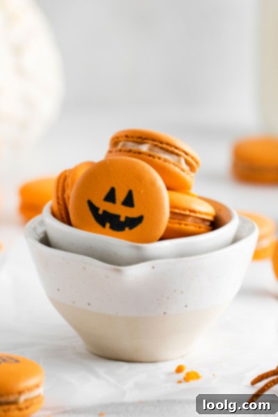 Close-up of a single pumpkin spice macaron with a Jack-o-lantern face.