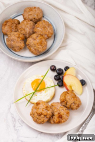 plate of sausage patties with a fried egg, sliced apple and blueberries