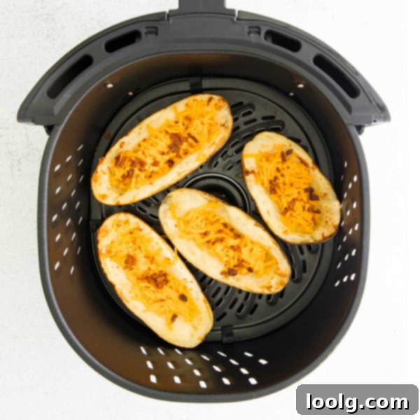 A close-up shot of golden-brown Air Fryer Potato Skins, stacked on a serving plate, with cheese and bacon visible.