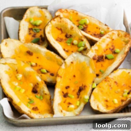 Image showing a plate full of Air Fryer Potato Skins loaded with melted cheddar cheese, crispy bacon and chopped chives.
