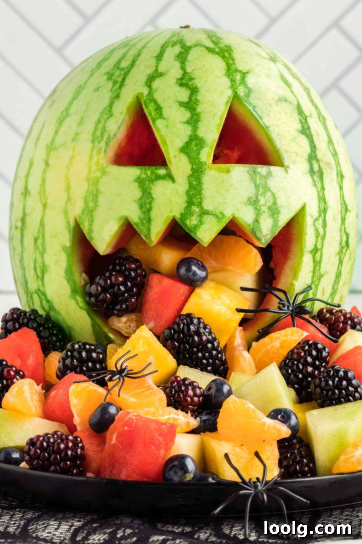 Close-up of a festive Halloween fruit salad, artfully arranged inside and spilling out of a carved watermelon shaped like a jack-o'-lantern, featuring a vibrant mix of fresh berries, melon, and other colorful fruits.