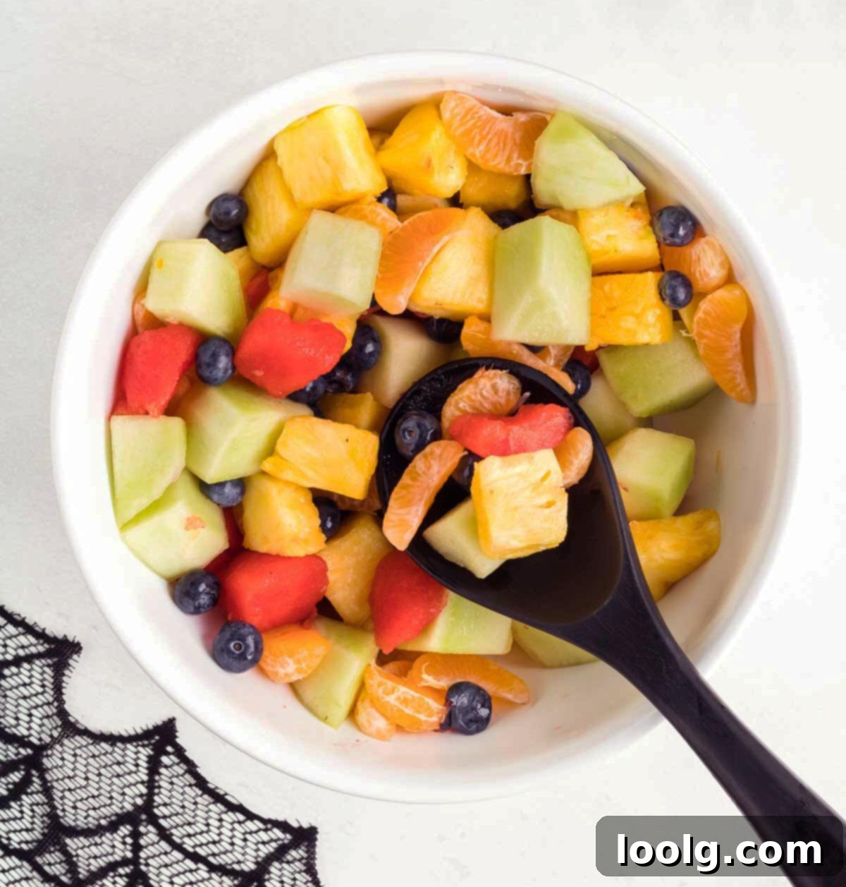 An overhead shot showcasing the vibrant and delicious Halloween fruit salad, presented in a carved watermelon jack-o'-lantern, brimming with a colorful assortment of fresh fruits, emphasizing its festive and healthy appeal.