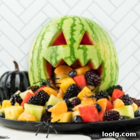 Image of a watermelon carved like a Jack-o'-lantern, overflowing with a vibrant Halloween fruit salad and garnished with fake spiders for a festive touch.