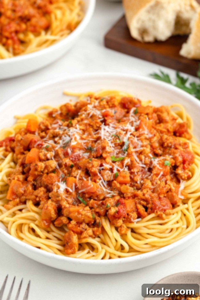 A beautifully plated dish of chicken bolognese with fresh pasta, garnished with herbs.