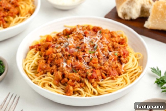 Chicken bolognese sauce served over gluten-free pasta, garnished with fresh basil.