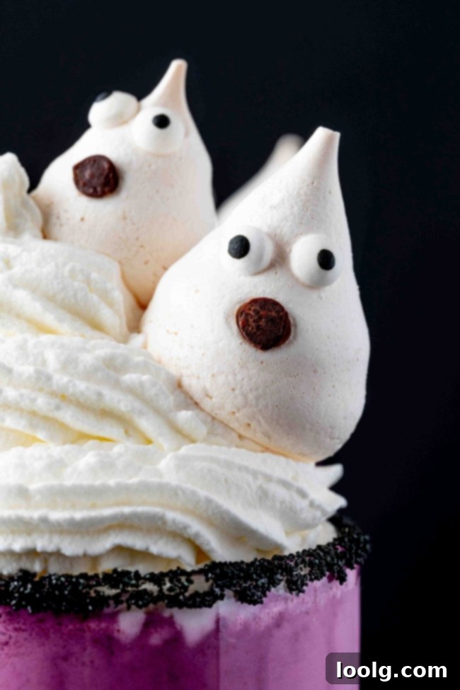Close-up of a Halloween milkshake showing the purple liquid, whipped cream, and meringue ghost details.