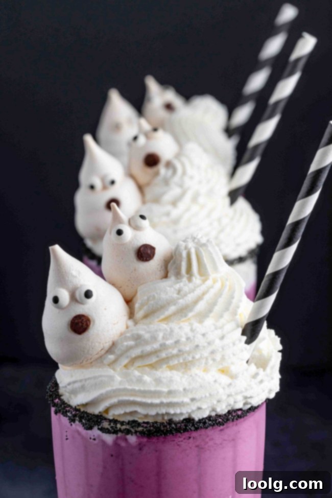 A Halloween milkshake in a decorated glass with whipped cream and a meringue ghost, viewed from a slightly different angle.
