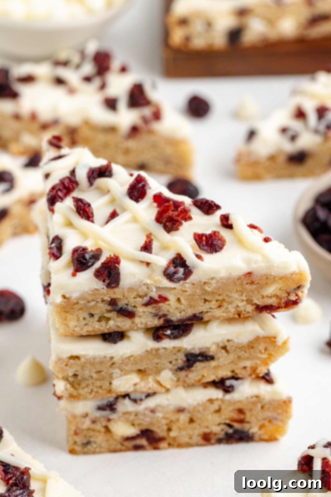 Close up of a pile of bliss bars showing the blondie base, white chocolate cream cheese frosting and cranberries.