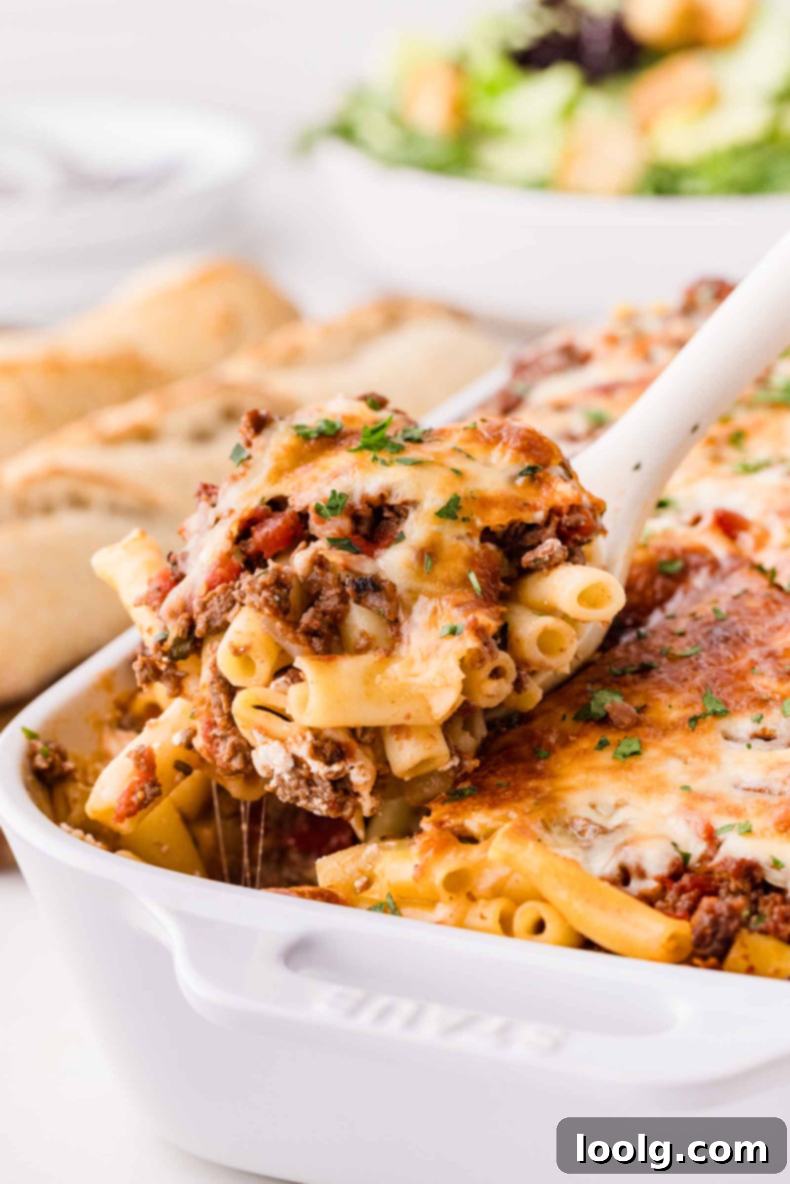 white spoon digging into casserole dish of venison baked ziti