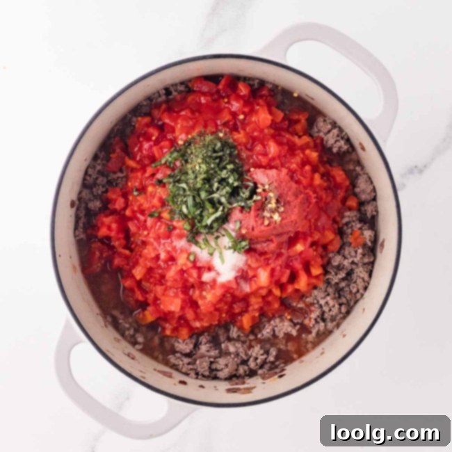 adding tomatoes and herbs to the sauce