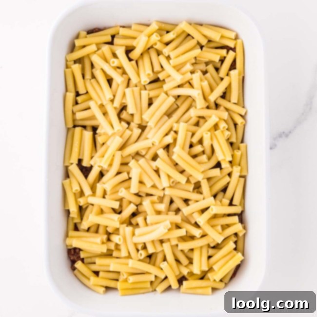 a layer of noodles being added on top of the sauce