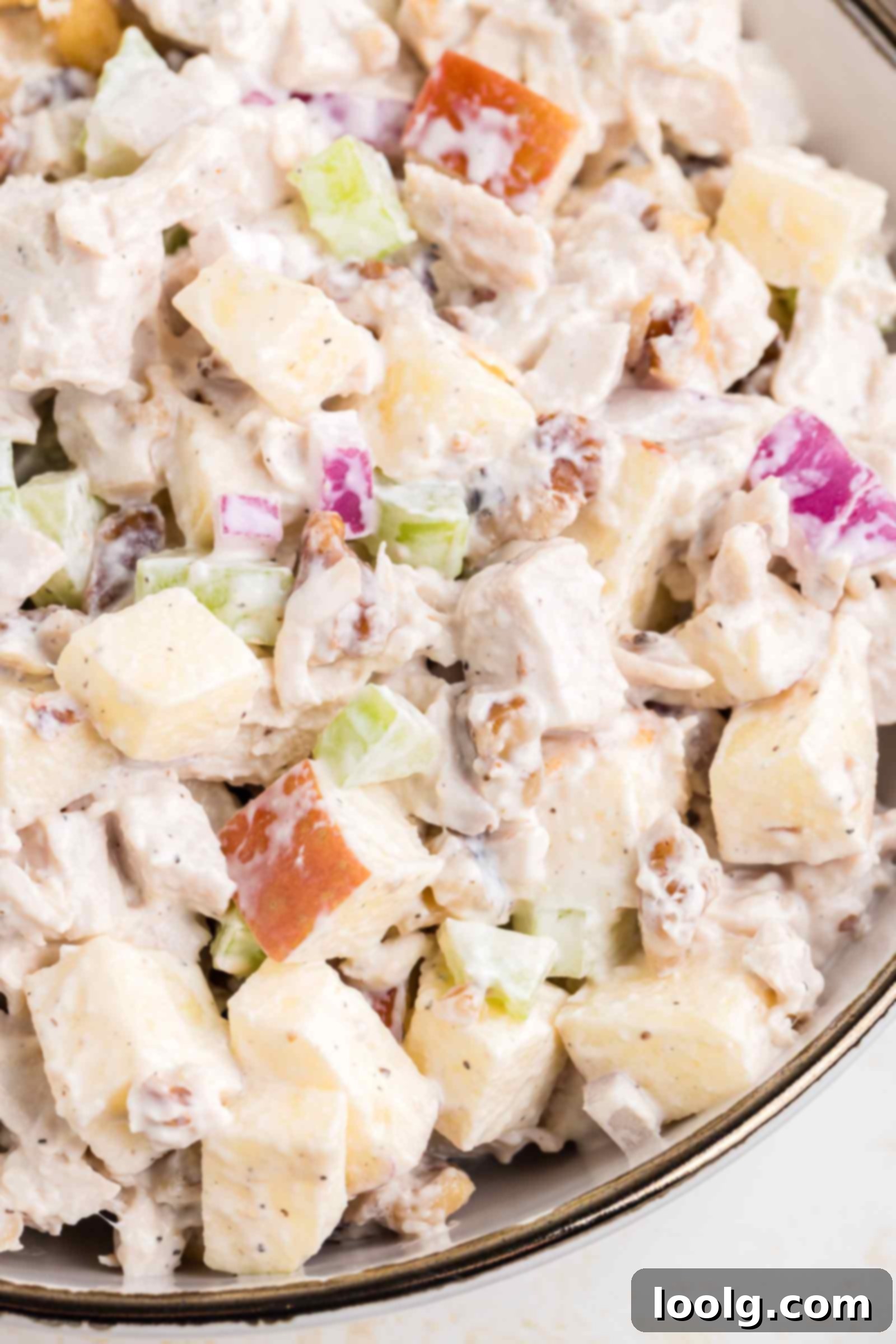 A close-up shot revealing the rich textures of the apple walnut chicken salad with creamy dressing, diced chicken, crisp apple chunks, and visible walnut pieces