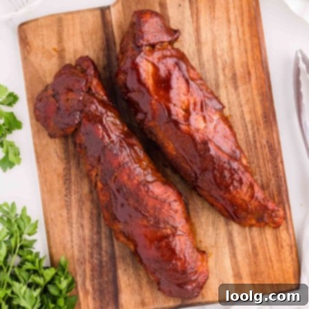 2 smoked pork tenderloins on a wooden cutting board with parsley in background