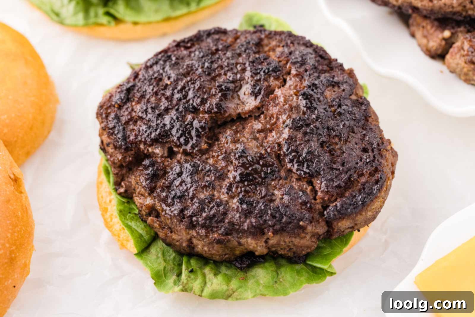 Close-up of a perfectly cooked venison hamburger on a bun topped with fresh green lettuce