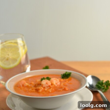 A top-down view of a bowl of Cajun Shrimp Soup, garnished with fresh herbs.