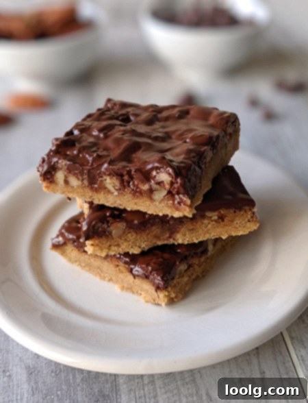 Delicious homemade Turtle Cookie Bars stacked on a plate, featuring a shortbread crust, caramel, pecans, and dark chocolate topping.